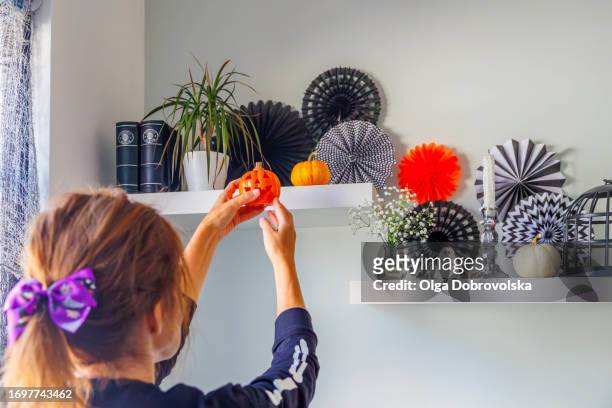close-up of woman hands decorating a shelf with a jack-o-lantern pumpkin - hair bow stock pictures, royalty-free photos & images