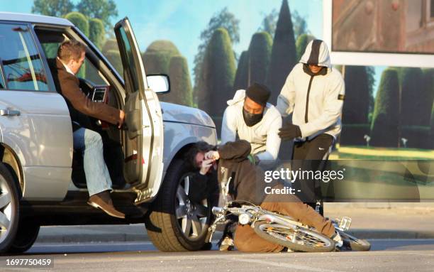 Scene four of a sequence of pictures shows two masked men knocking a cyclist to the ground and stealing his bag during a street robbery, in front of...