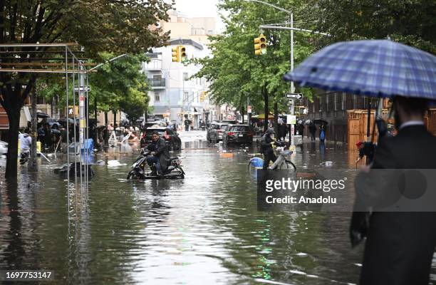 Man tries to pass a flooded street with his bicycle after a heavy rain in Williamsburg, New York, United States on September 29, 2023.