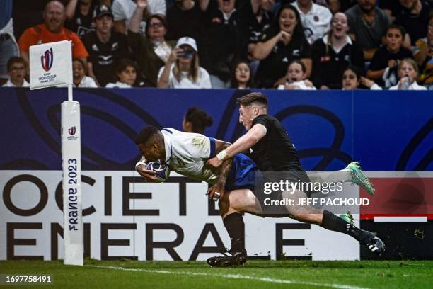 Italy's left wing Monty Ioane dives and scores a try as he is tackled by New Zealand's scrum-half Cam Roigard during the France 2023 Rugby World Cup...