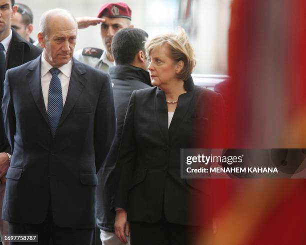 German Chancellor Angela Merkel looks at her host as she inspects the guard of honor along with Israeli Prime Minister Ehud Olmert during a welcoming...