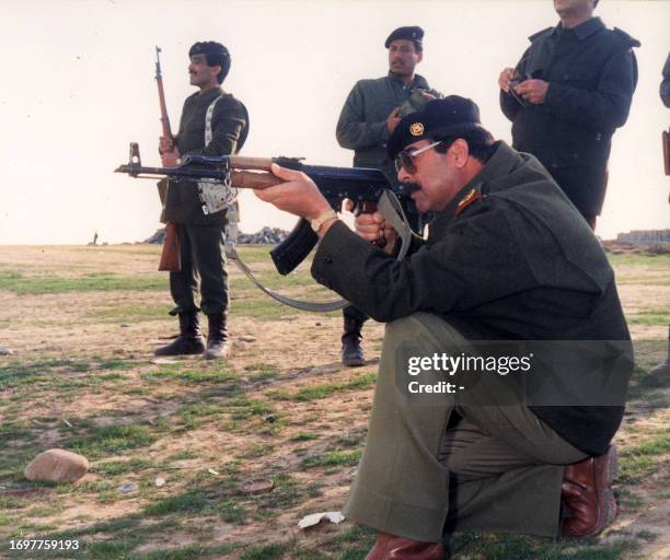 This handout file picture taken in 1987 shows Iraqi President Saddam Hussein pointing a kalashnikov at an unspecified location in Iraq. Baghdad has...