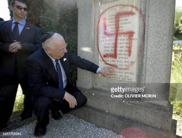 Knesset President Reuven Rivlin looks at a tomb which was defaced with a swastika during a ceremony at Herrlisheim's Jewish cemetery where 127 graves...