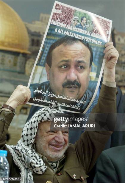 Palestinian leader Yasser Arafat holds a poster of jailed leader of the Fatah movement in the West Bank and leading proponent of the Palestinian...