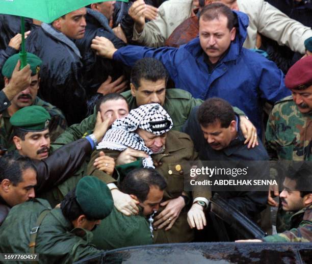 Security guards and aides, including his personal guard Yussef al-Abdallah , help Palestinian leader Yasser Arafat into his car after he felt tired...