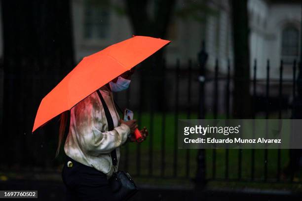 Woman walk under rain during a coastal storm at Lower Manhattan on September 29, 2023 in New York City. Flash flooding is expected in the counties of...