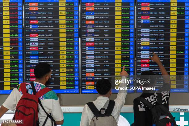 Passengers seen check a flight at a flight information display screen at Suvarnabhumi International Airport. The new SAT-1 terminal at Suvarnabhumi...