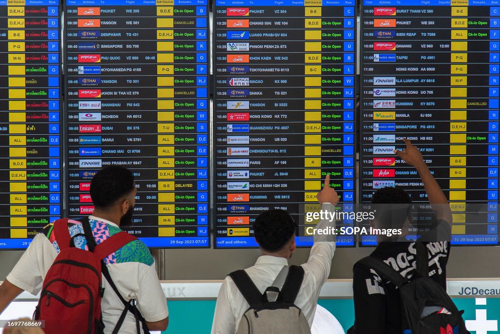 Passengers seen check a flight at a flight information display screen ...