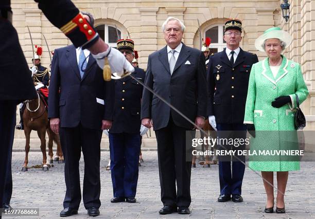 Britain's Queen Elizabeth II, right, and French Senate President Christian Poncelet, center, stand at attention during a ceremony at the Senate in...