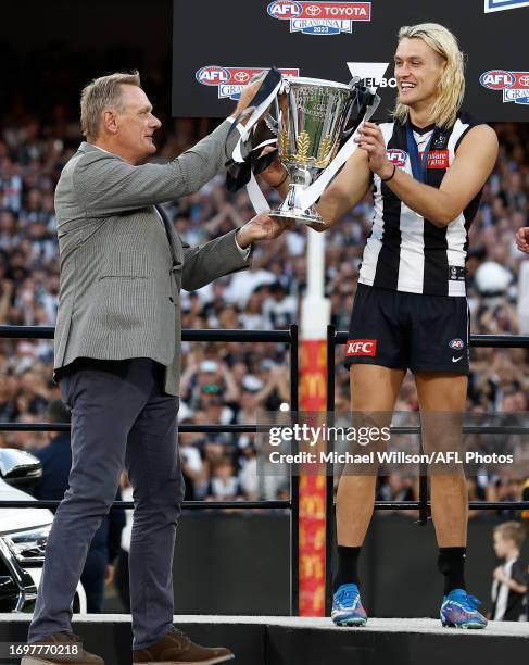 Peter Moore hands son Darcy Moore of the Magpies the Premiership Cup during the 2023 AFL Grand Final match between the Collingwood Magpies and the...