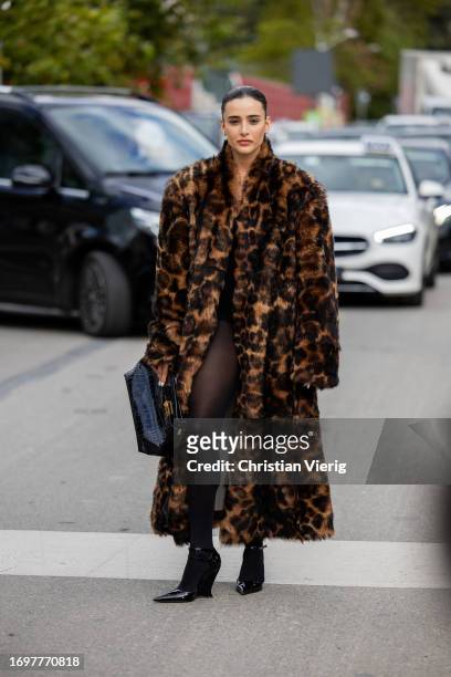 Livia Nunes Marques wears oversized tiger animal print faux fur coat, black bag, tights outside Ferragamo during the Milan Fashion Week - Womenswear...