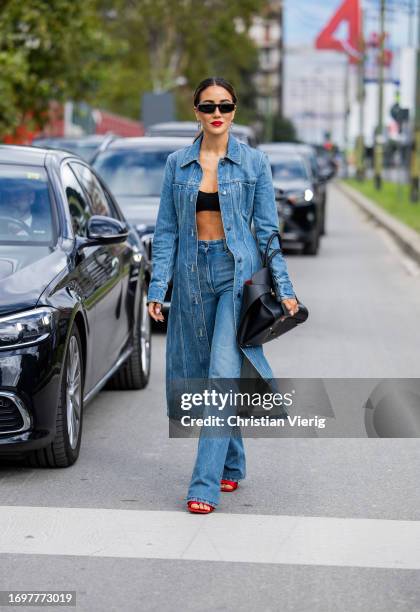 Tamara Kalinic wears denim coat, jeans, black bag, red sandals, black cropped top outside Ferragamo during the Milan Fashion Week - Womenswear...