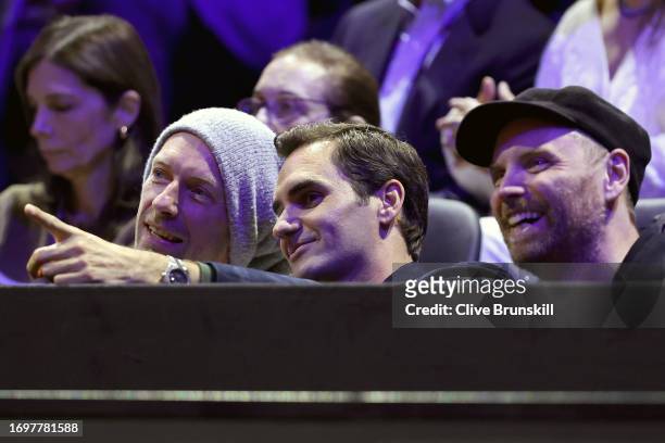 Singer Chris Martin of Coldplay, former ATP player Roger Federer, and guitarist Jonny Buckland of Coldplay react during a match during day two of the...