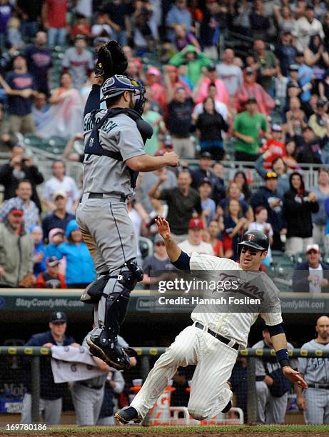Kelly Shoppach of the Seattle Mariners jumps for the ball as Joe Mauer of the Minnesota Twins slides safely into home plate to score the winning run...