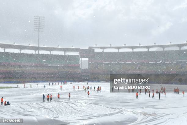 Ground staff cover the pitch as play is delayed due to rain before the start of a warm-up match between India and England ahead of the ICC Men's...