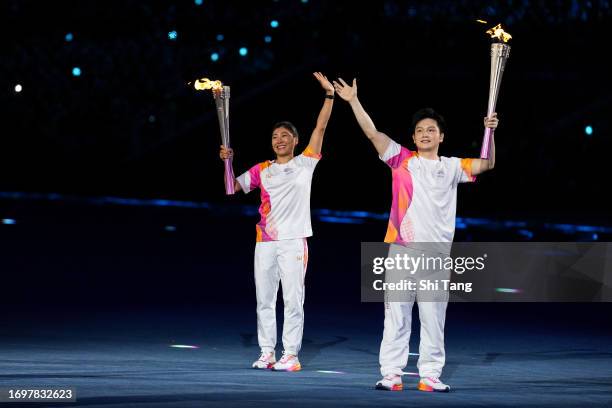 Torch bearers China table tennis player Fan Zhendong and China aerial skier Xu Mengtao hold the Asian Games flames during the opening ceremony of the...