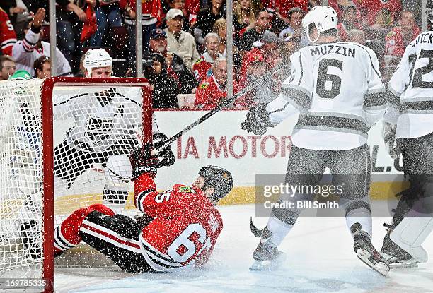 Andrew Shaw of the Chicago Blackhawks slides into the goal past Jake Muzzin of the Los Angeles Kings as Matt Greene of the Kings watches from behind...