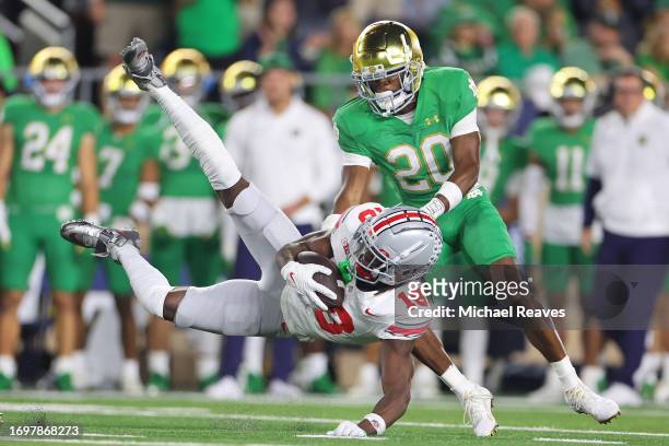Marvin Harrison Jr. #18 of the Ohio State Buckeyes is tackled by Benjamin Morrison of the Notre Dame Fighting Irish after a reception during the...