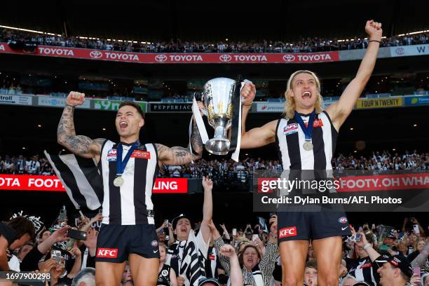 Jamie Elliott and Darcy Moore of the Magpies celebrate with the premiership cup during the 2023 AFL Grand Final match between the Collingwood Magpies...