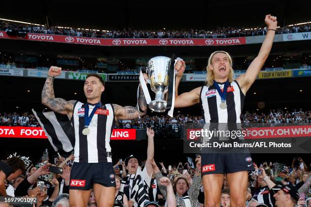 Jamie Elliott and Darcy Moore of the Magpies celebrate with the premiership cup during the 2023 AFL Grand Final match between the Collingwood Magpies...