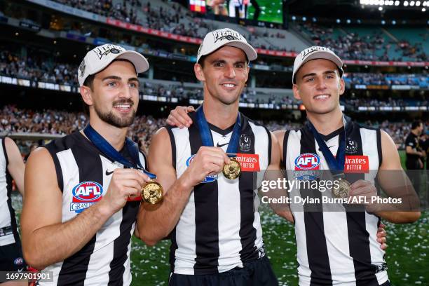 Josh Daicos, Scott Pendlebury and Nick Daicos of the Magpies pose with their premiership medals during the 2023 AFL Grand Final match between the...