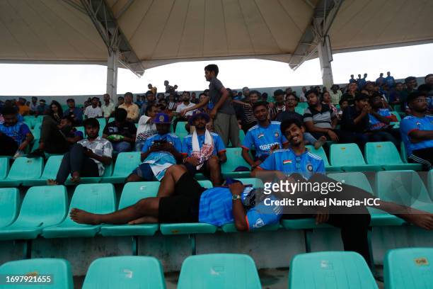 Spectators wait as play is delayed due to rain during the ICC Men's Cricket World Cup India 2023 warm up match between India and England at Barsapara...