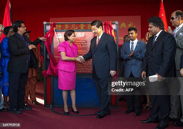 China's President Xi Jinping and Prime Minister of Trinidad and Tobago Kamla Persad-Bissessar shake hands at the site of the Couva Children´s...