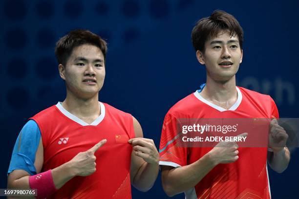China's men's doubles players Liang Weikeng and Wang Chang point to the national flag on their jerseys after beating Japan's Takuro Hoki and Yugo...