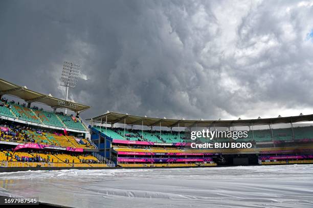 Clouds looms over the sky and the covered pitch as rain delayed the warm-up match between India and England at the Assam Cricket Association Stadium,...