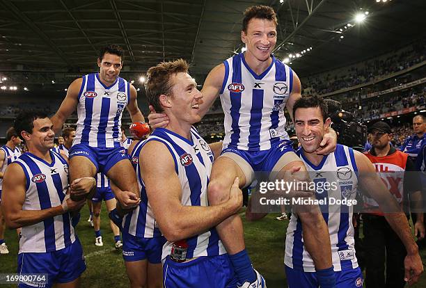 Daniel Wells of the Kangaroos gets carried off by Lindsay Thomas and Scott Thompson for his 200th game and and Brent Harvey gets carried off by Drew...