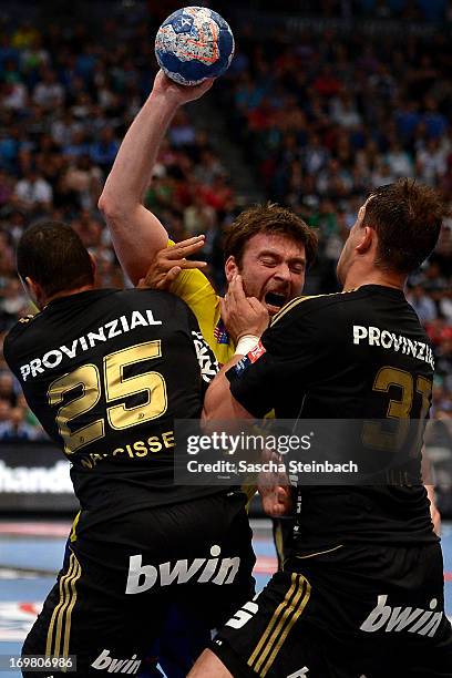 Rastko Stojkovic of Kielce is tackled by Daniel Narcisse and Momir Ilic of Kiel during the EHF Final Four third place match between KS Vive Targi...