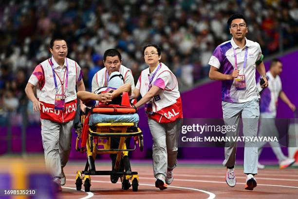 An official leaves the track and field on a stretcher after his leg was injured by a stray hammer during the men's hammer throw final athletics event...