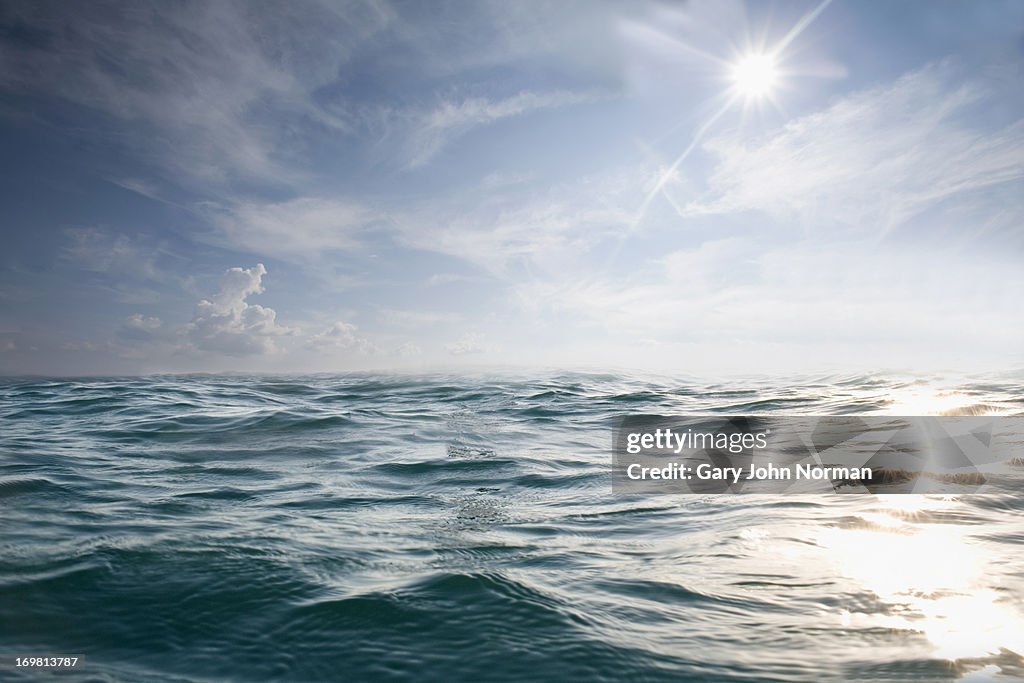 Choppy blue sea with blue sky and sun