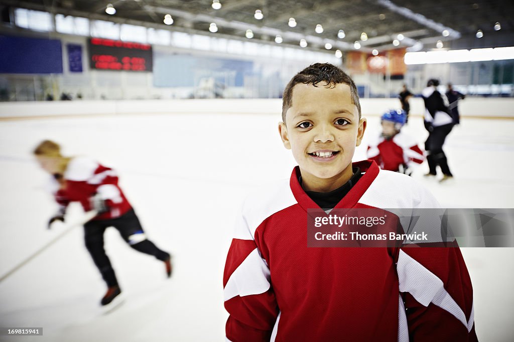 Smiling young hockey player standing on ice