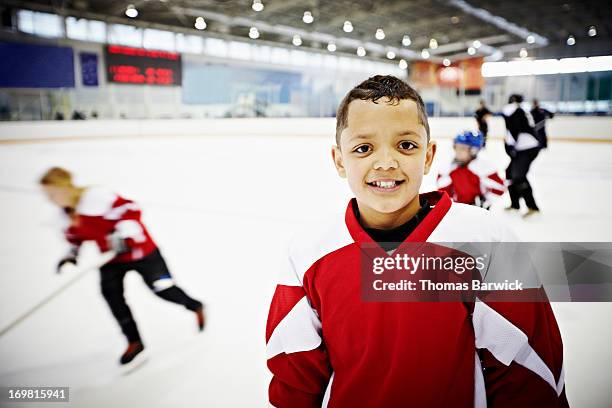 smiling young hockey player standing on ice - kids ice hockey stock pictures, royalty-free photos & images