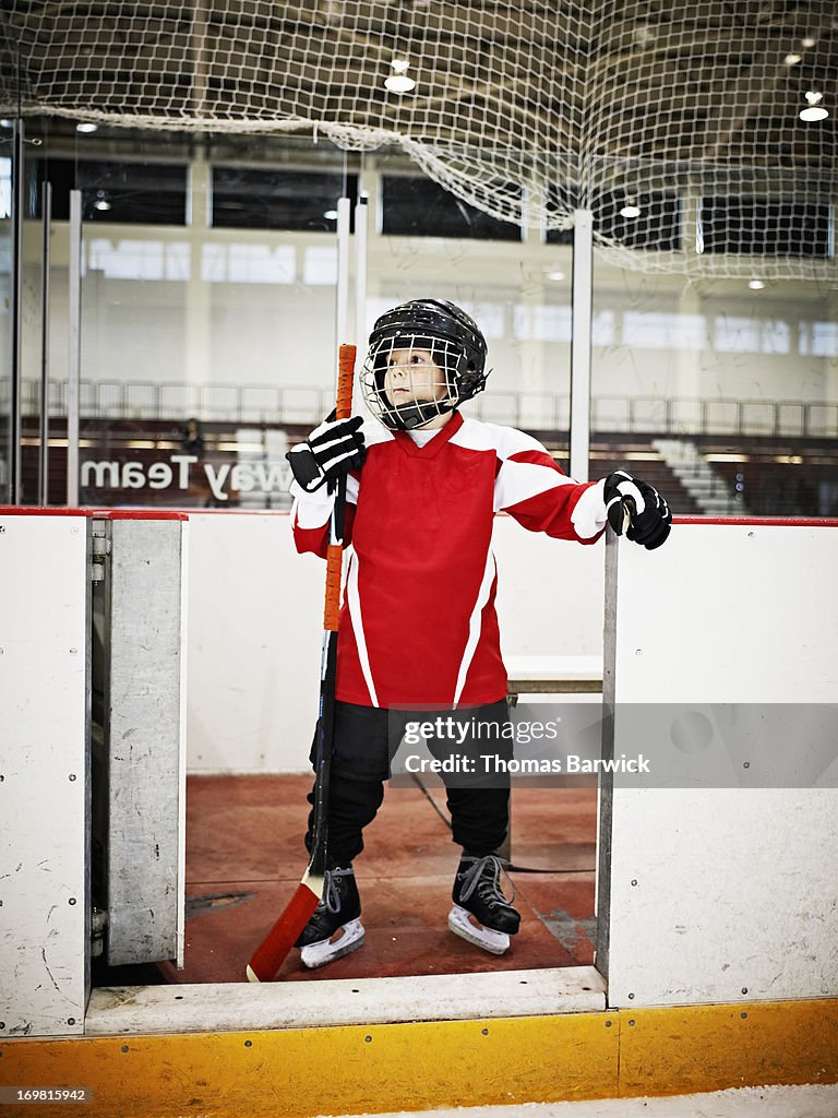 Young hockey player standing in players box