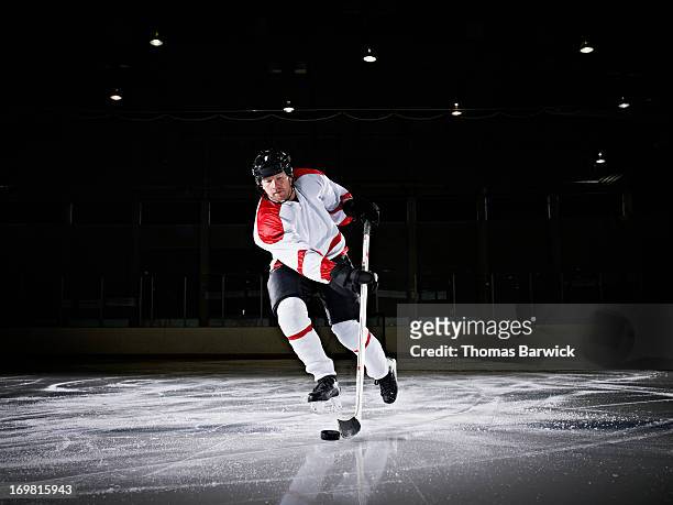 ice hockey player skating down ice with puck - hockey player stock-fotos und bilder