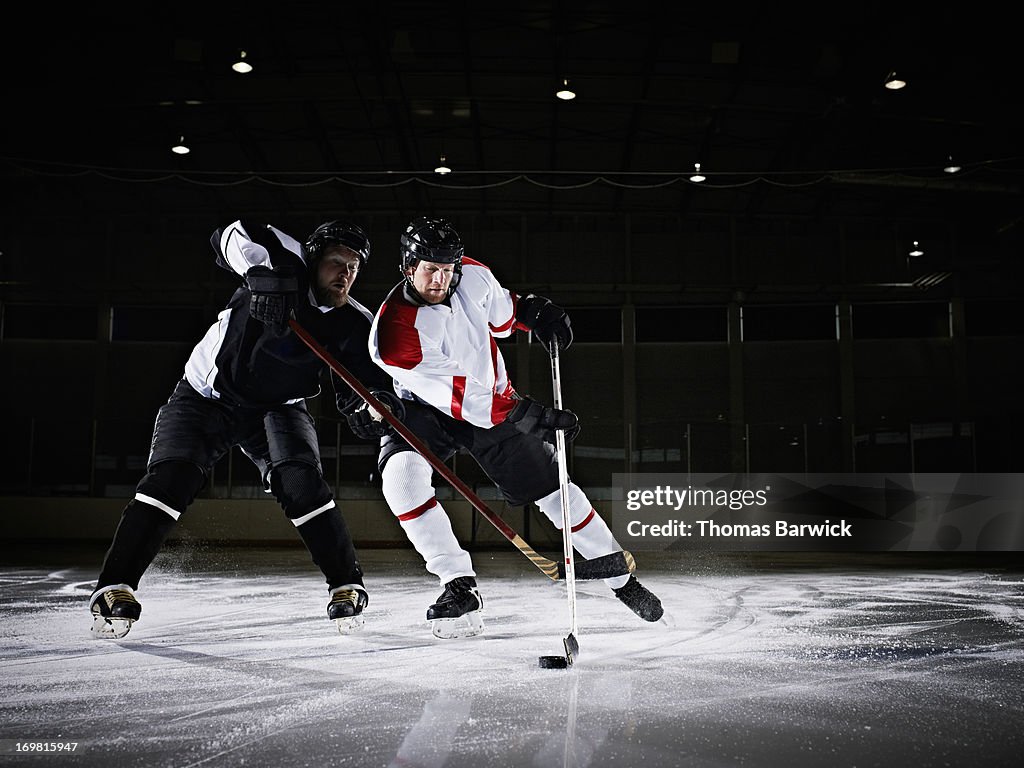 Ice hockey players battling for puck in arena