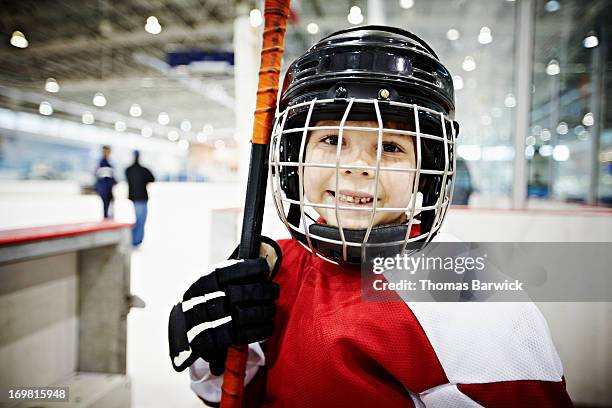 smiling young hockey player in players box - kids ice hockey stock pictures, royalty-free photos & images