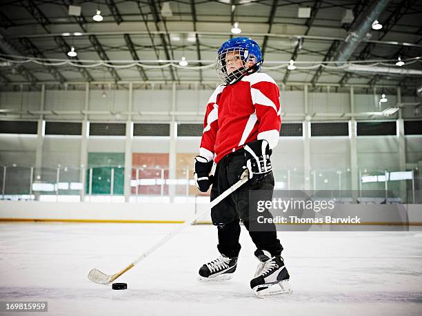 young male ice hockey player standing on ice - hockey kids stock-fotos und bilder