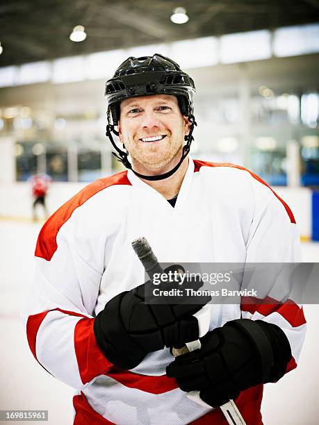 smiling ice hockey player standing on ice - sports glove stock-fotos und bilder