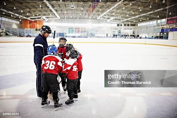 ice hockey coach encouraging young team - kids ice hockey stock pictures, royalty-free photos & images