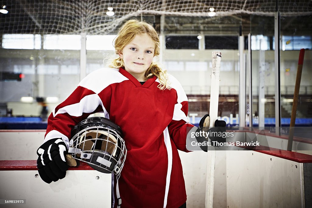 Young female ice hockey player in players box