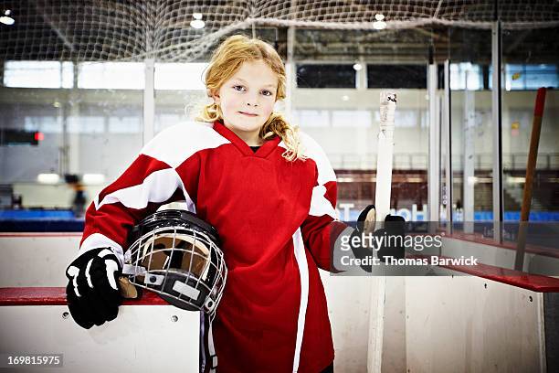 Young female ice hockey player in players box