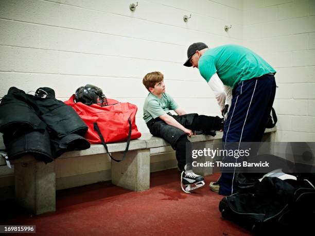 father helping young player with skates - hockey kids stock-fotos und bilder