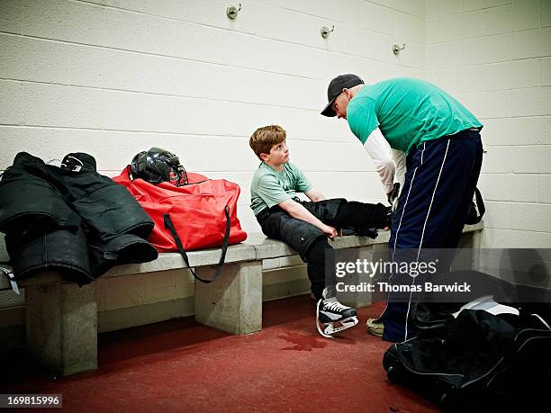 father helping young player with skates - strict parent fotografías e imágenes de stock