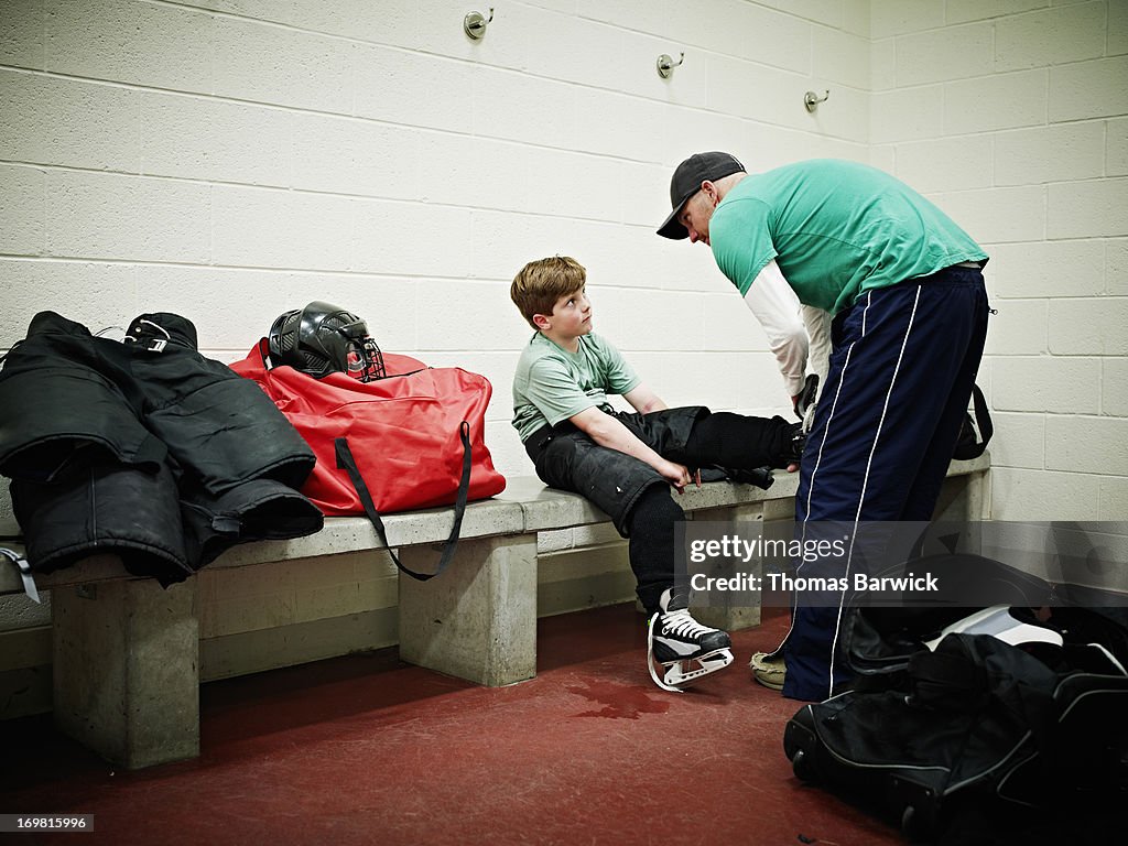 Father helping young player with skates