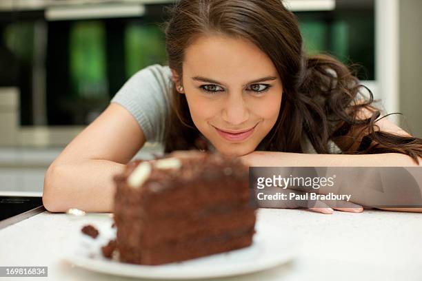 frau schaut auf schokoladenkuchen - temptation stock-fotos und bilder