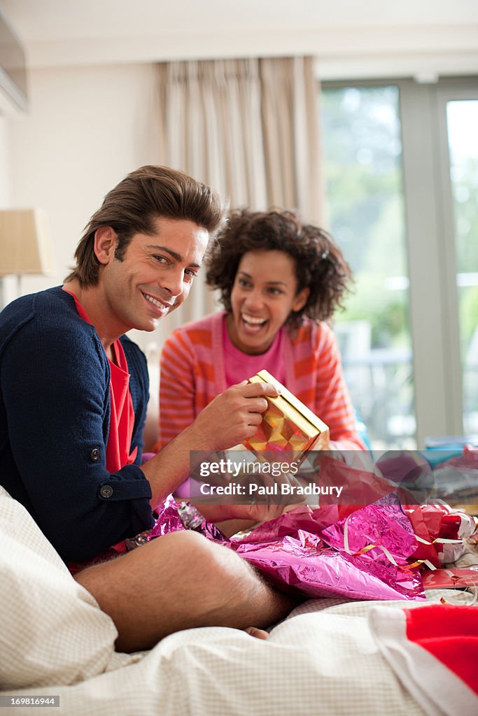 Couple opening gifts on bed