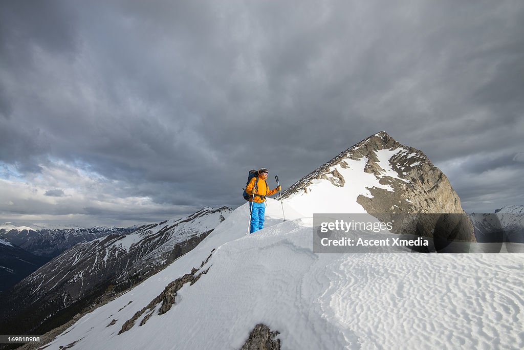 Mountaineer stands on summit ridgecrest, sunrise